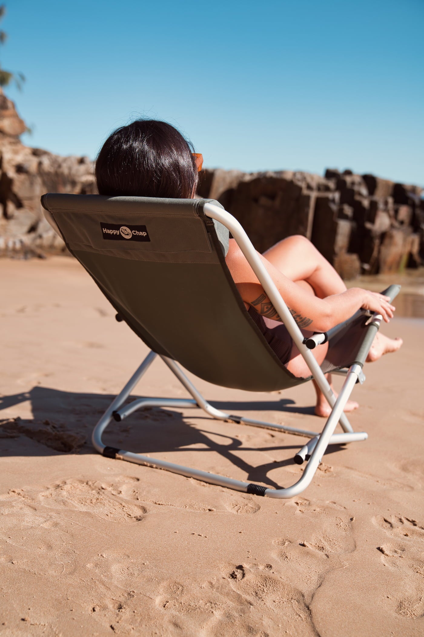 Person sitting on a happy chap chair on a rocky beach